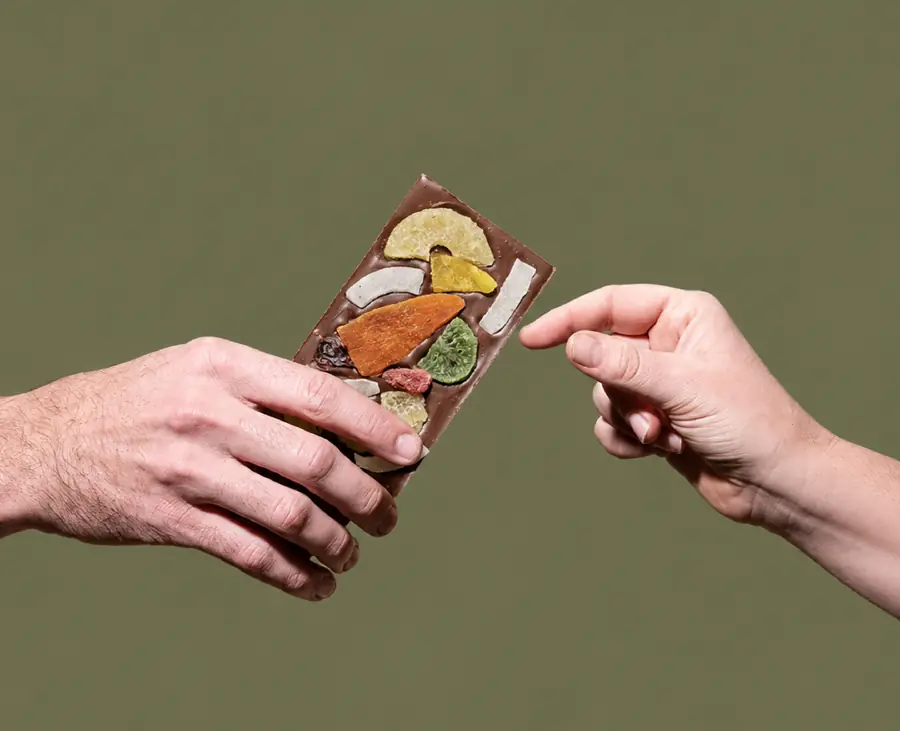 One hand passing a chocolate bar to another