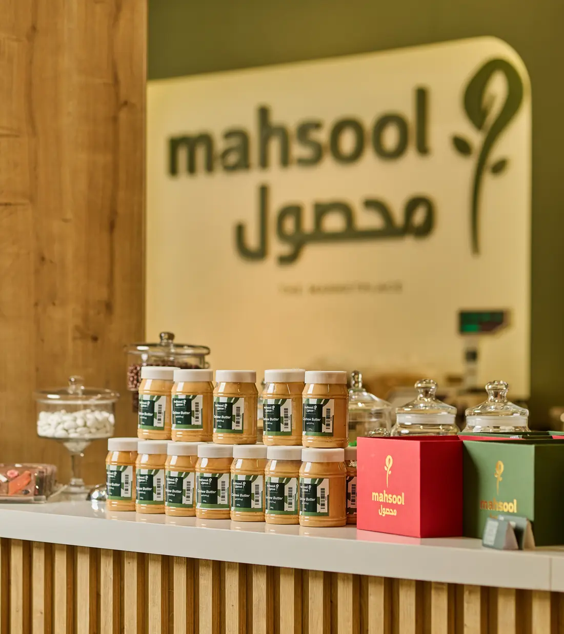 Mahsool store counter with jars of nut butter under the logo wall